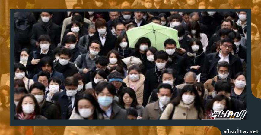 مواطنون يسيرون في أحد شوارع طوكيو الرئيسية مع الالتزام بارتداء الكمامة